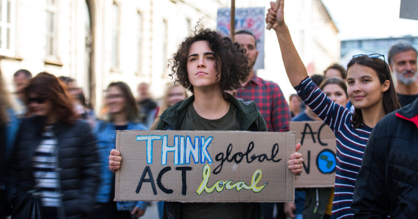 woman holding sign that says think global act local